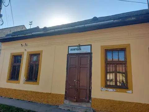 Single-storey ochre house with barred windows and a Лончић 1884 board over brown double doors