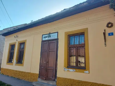 The ochre front from the corner, house number 8 on the wall beside a barred window