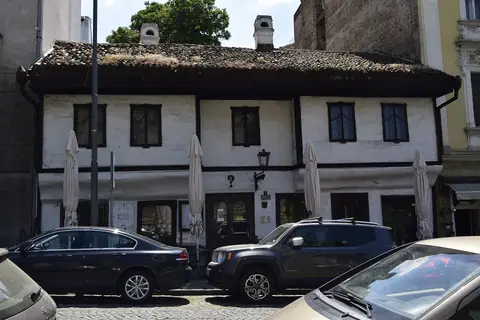 A low white house with a pantiled roof and dark timber banding, a small question mark painted on the front between the windows