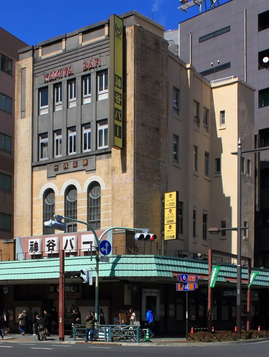 Four-storey buff-brick bar building with red roof lettering and a tall vertical sign in Japanese