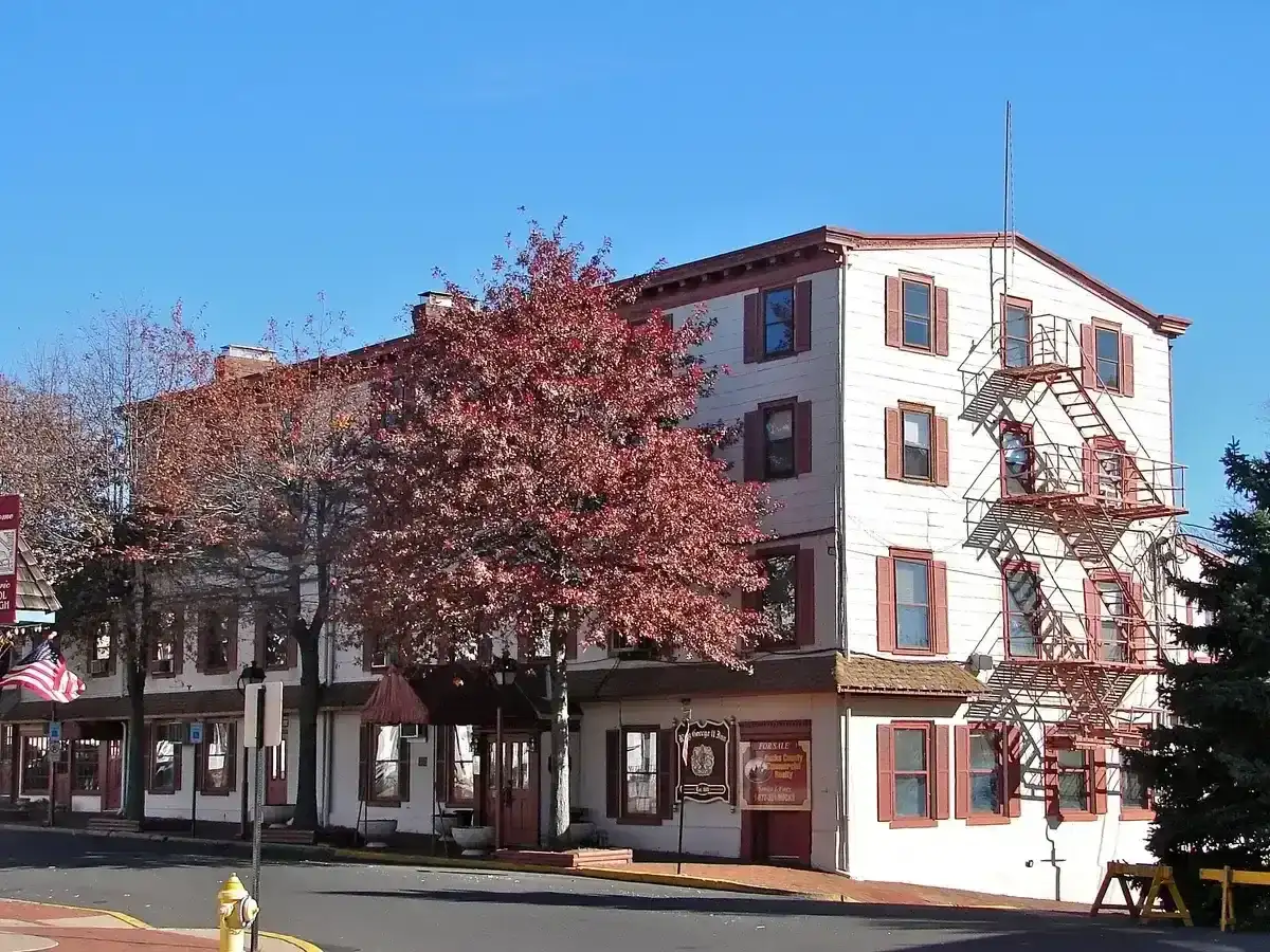 Long white clapboard inn of three storeys with shuttered windows and an iron fire escape