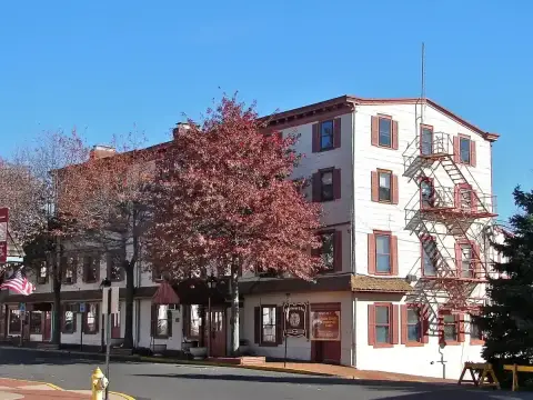 Long white clapboard inn of three storeys with shuttered windows and an iron fire escape