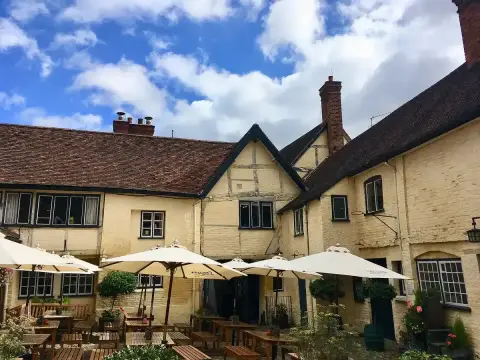 Sunlit courtyard of stone and timber ranges with parasols and benches over the cobbles