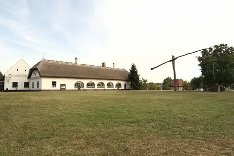 Long thatched white inn across a green, KONDOROSI CSÁRDA on the gable and a sweep well beside it