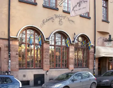 Three arched windows under the painted Restaurang Aktiebolaget Kvarnen lettering and a windmill