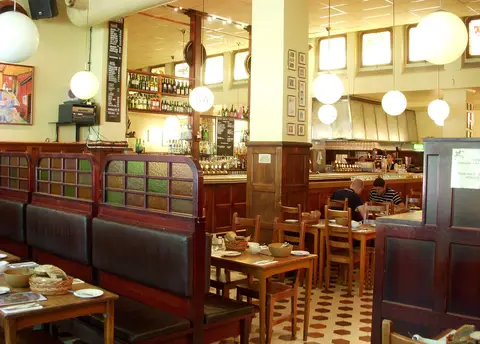 Panelled dining room with high-backed booths, globe lamps and a long bar along the back wall