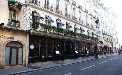 Long black frontage with awnings and lanterns, seen down the street with a cyclist passing