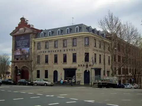 Three-storey sandstone corner hotel with dormered slate roof and its name painted along the wall