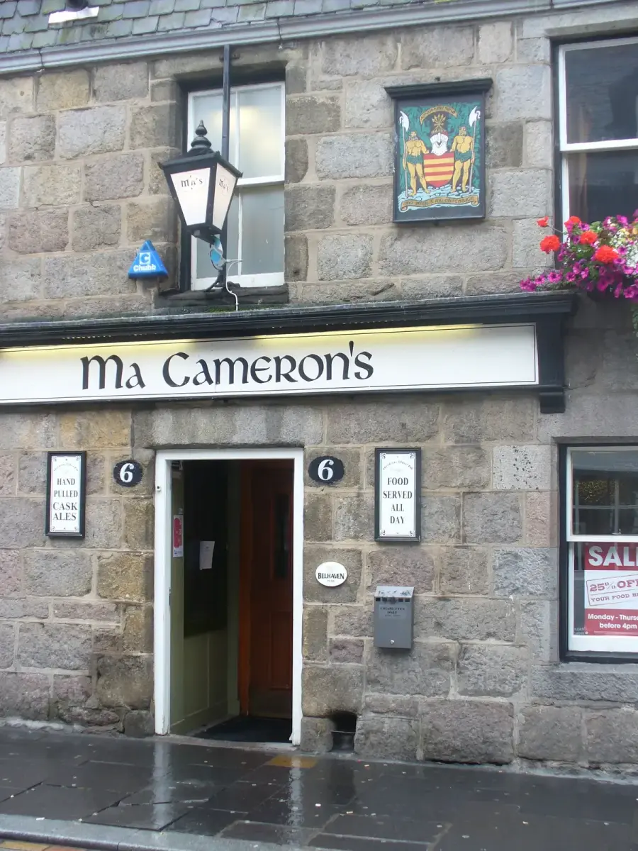 Grey granite frontage with a white lettered fascia, a lantern and the burgh arms above the door