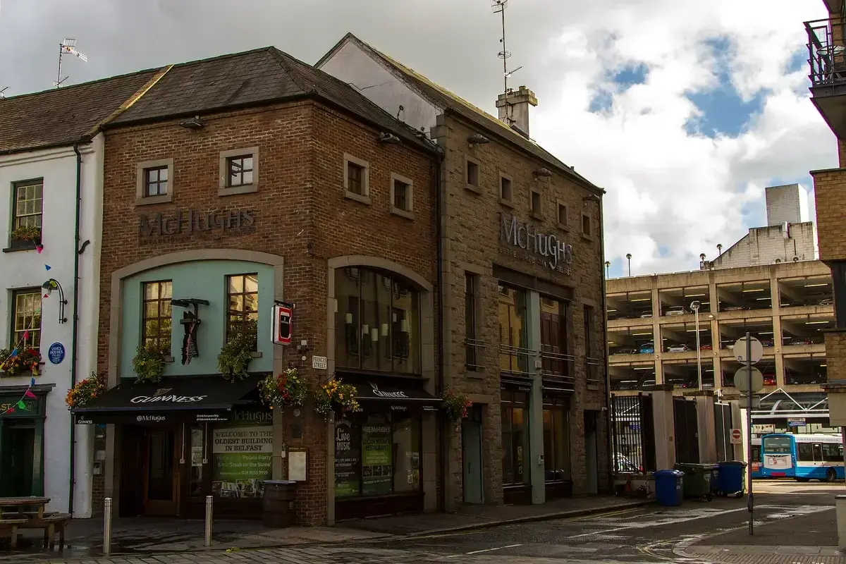 Brick and stone corner bar of three storeys with green-painted shopfronts and hanging baskets
