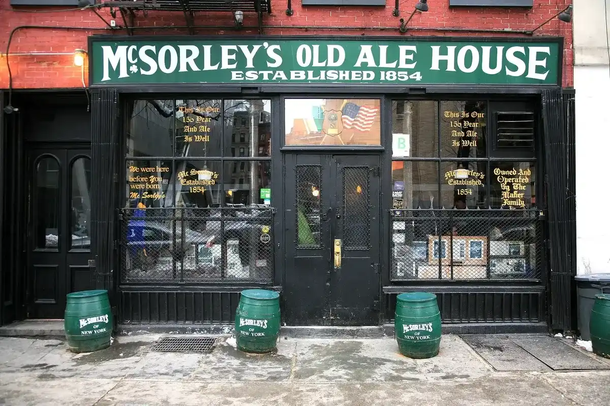 Green and gold painted shopfront with barred windows, gold sign lettering and green beer barrels