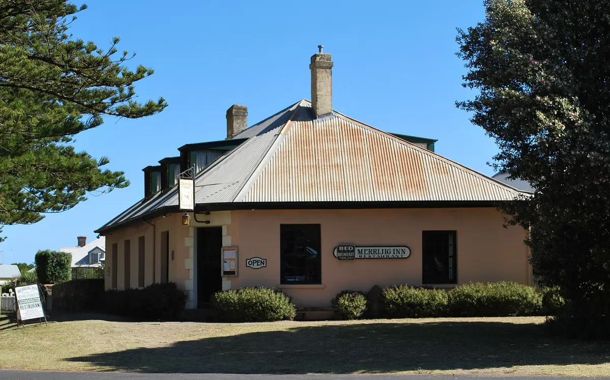 Low pink-rendered inn with a corrugated iron roof and a sign reading Merrijig Inn Restaurant