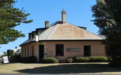 Low pink-rendered inn with a corrugated iron roof and a sign reading Merrijig Inn Restaurant