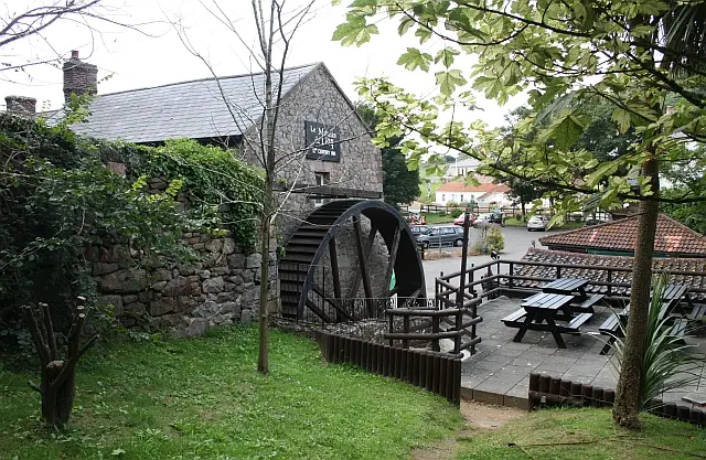 Le Moulin de Lecq, a stone watermill turned pub, with its iron wheel and benches outside