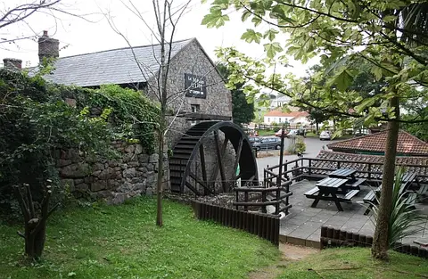 Le Moulin de Lecq, a stone watermill turned pub, with its iron wheel and benches outside
