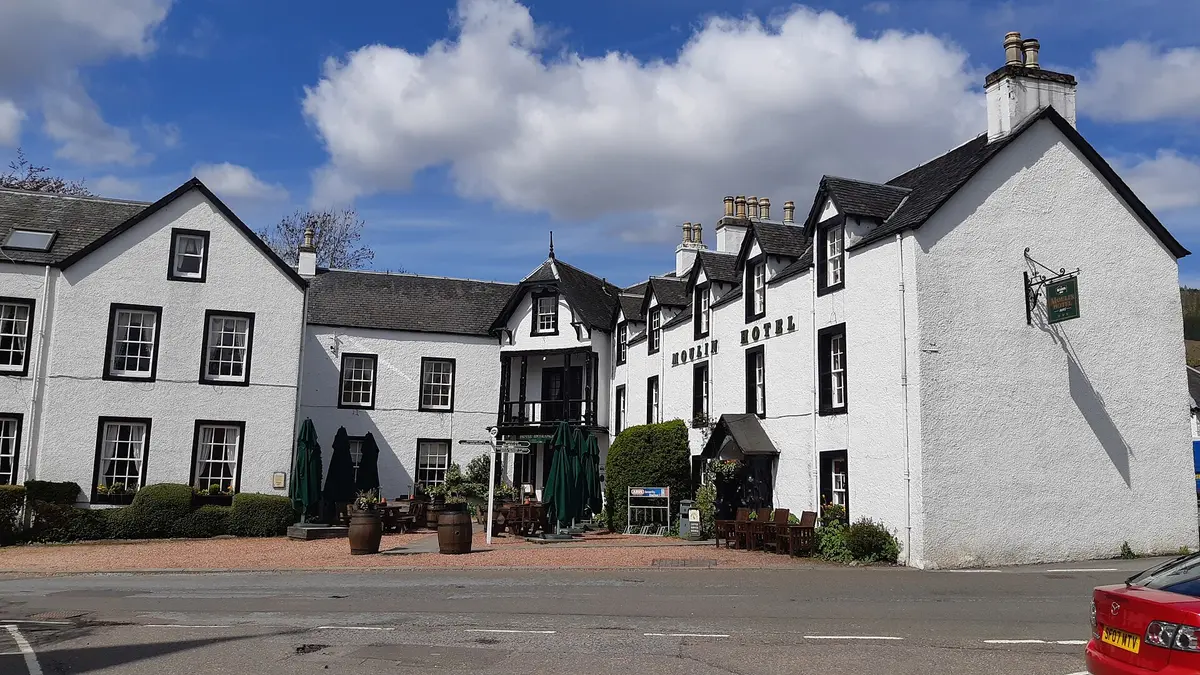 The white harled front of the Moulin Hotel, gilt lettering on the gable and barrels beside the door