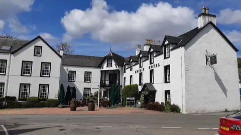 The white harled front of the Moulin Hotel, gilt lettering on the gable and barrels beside the door