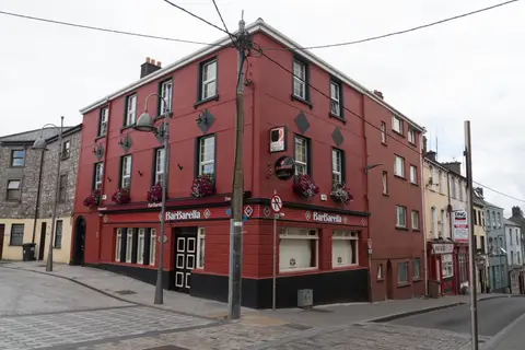Red-painted three-storey corner pub on Barrack Street, Cork, trading as BarBarella, with diamond plaques and window boxes
