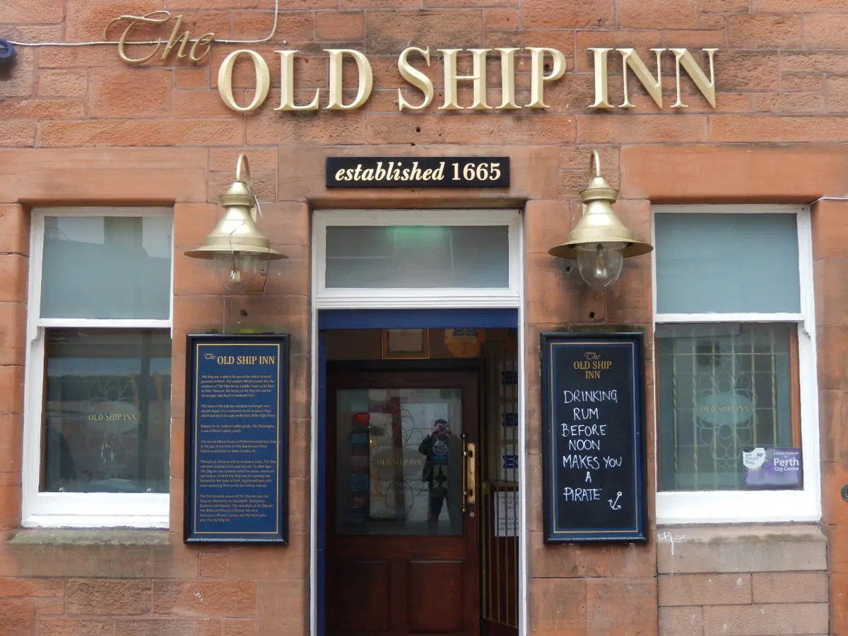 A red sandstone frontage with The Old Ship Inn in gold letters and a panel below reading established 1665