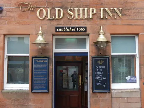 A red sandstone frontage with The Old Ship Inn in gold letters and a panel below reading established 1665