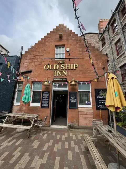 The crow-stepped red sandstone front of the Old Ship Inn, its name in gold above the door, bunting across