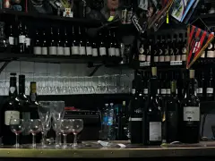 Behind the bar at the Osteria del Sole: shelves of wine bottles labelled vino bianco and vino nero, glasses and a Bologna FC pennant