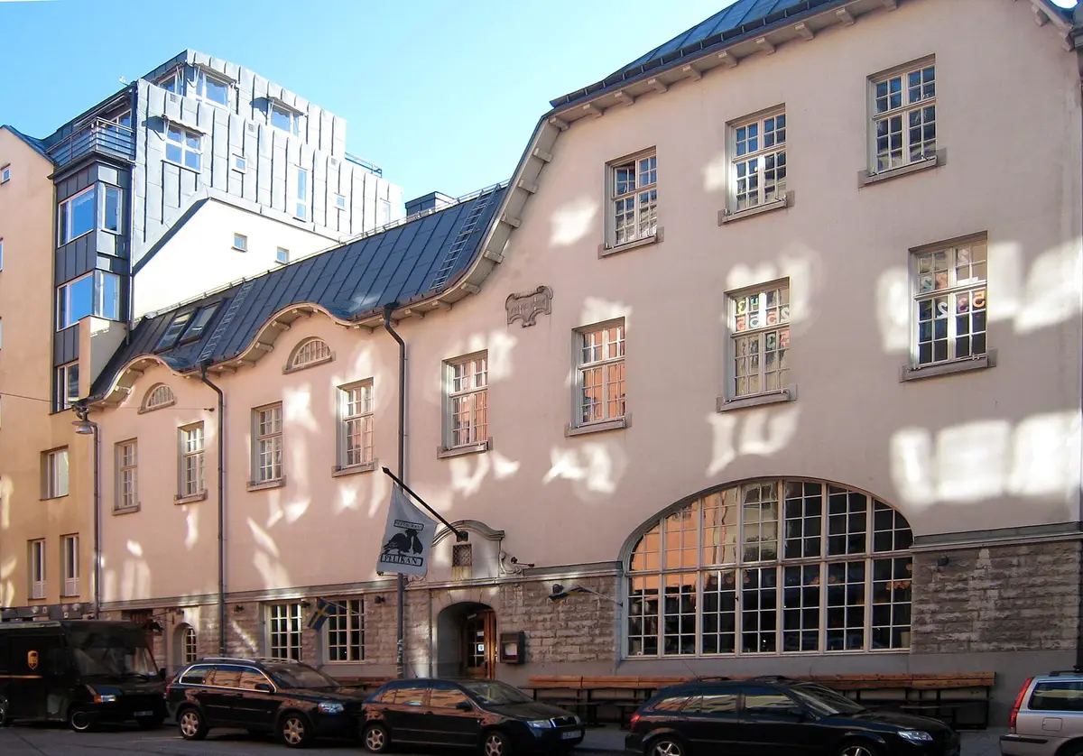 Long rendered beer hall on Blekingegatan with a pelican flag sign and a tall arched window
