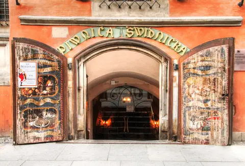 The arched entrance to Piwnica Świdnicka, its name in gold letters above painted doors