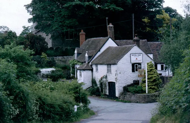 The white-rendered Royal Oak at the bend of a lane in 1992, its inn sign on a post by the road