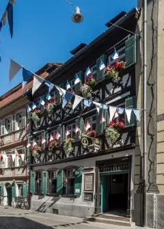 Half-timbered tavern with green shutters, window boxes and bunting over the cobbled street