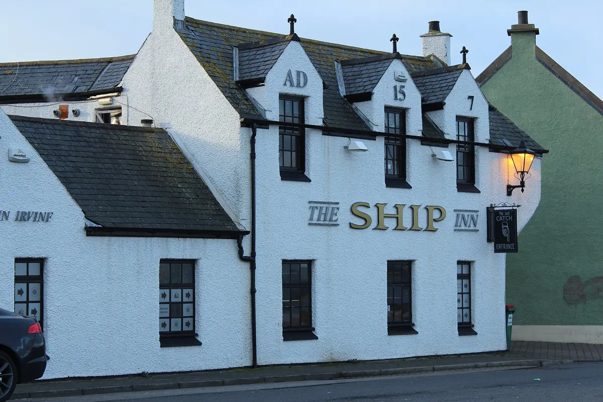 The white harled gable of the Ship Inn, its name in gold letters and a date picked out across the dormers