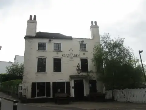 Cream-painted brick inn with two tall chimneys and a lamp over the door, benches outside