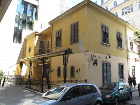 Corner of a yellow baroque palace, a striped awning over the restaurant terrace and an iron sign bracket