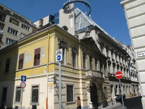 Yellow palace on a street corner, baroque portal and balcony, shuttered windows above