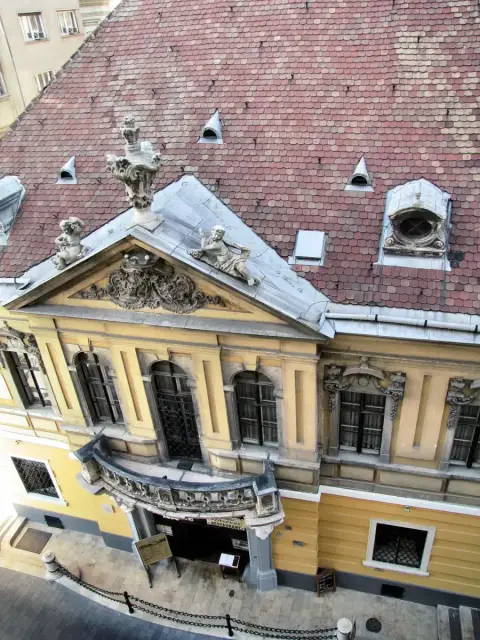 Tiled roof and carved pediment above the restaurant's doorway, seen from a window across the street