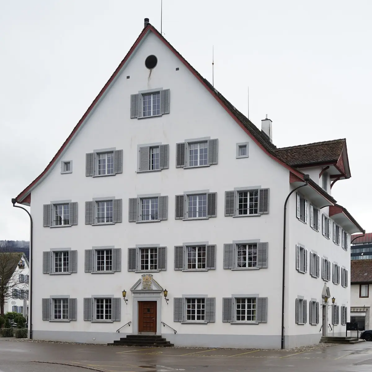 White gabled tavern with grey shutters and a panelled oak door under a carved 1703 pediment