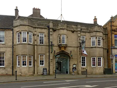 Stone front under a grey sky, the hanging angel sign to the right of the arch