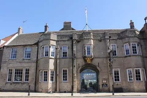 Stone front with a carriage arch, a gilded angel above it and mullioned windows either side