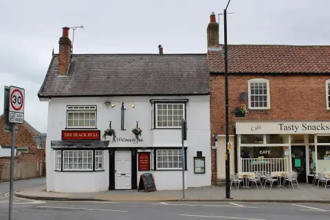 Rendered inn beside a red-brick cafe, sash bay windows and a black-lettered name board