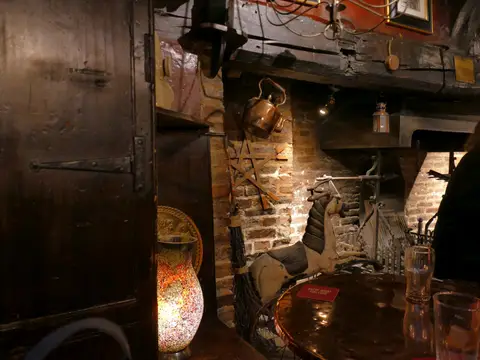 The inglenook inside the Black Swan, with a copper kettle, a rocking horse and a besom beside the hearth