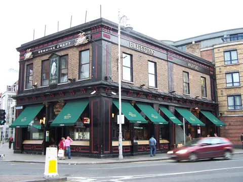 The brick corner of the Bleeding Horse, green awnings out and traffic passing