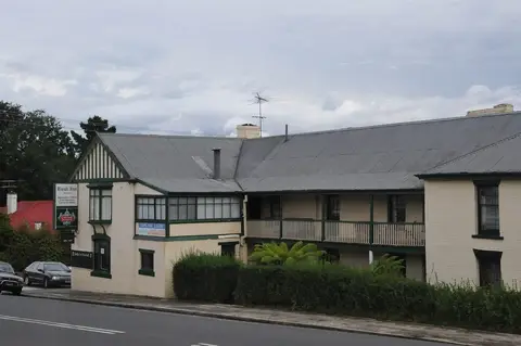Long cream weatherboard inn with a two-storey veranda and a grey roof, seen from across the road