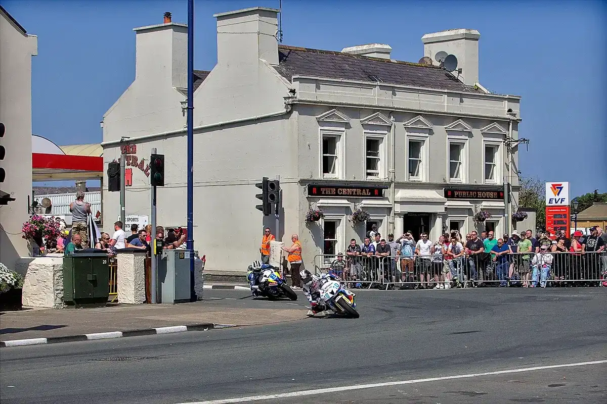 The grey two-storey Central on Parliament Square, Ramsey, with THE CENTRAL and PUBLIC HOUSE fascias, as TT riders pass the barriers