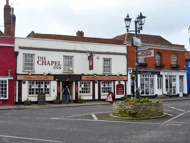 The white front of the Chapel Inn at Coggeshall, its name in red above the windows and a lamp over the door