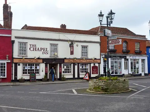 The white front of the Chapel Inn at Coggeshall, its name in red above the windows and a lamp over the door