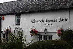 White rendered wall under a slate roof with the inn's name and AD 1028 painted in black lettering