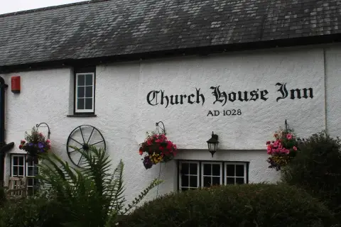 White rendered wall under a slate roof with the inn's name and AD 1028 painted in black lettering