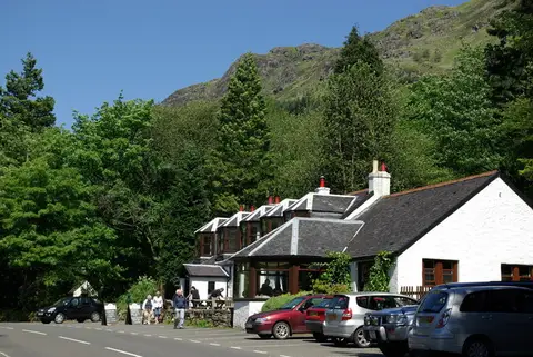 The white Coylet Inn beside the road at Loch Eck, cars outside and hills behind