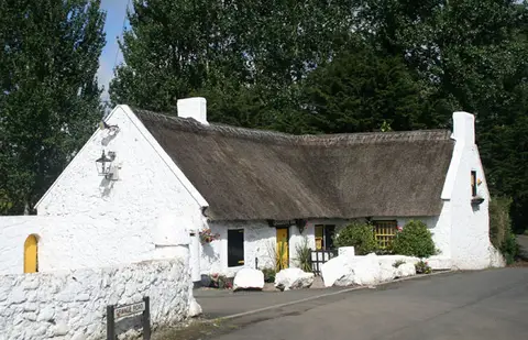 The long thatched roof and white gable of the Crosskeys Inn seen from the roadside