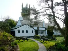 The whitewashed Crown Inn at Lanlivery with picnic benches and the church tower behind